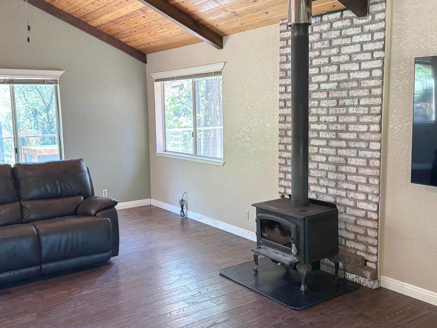 Living room with wood-burning stove set against a white brick hearth under the open beam ceiling