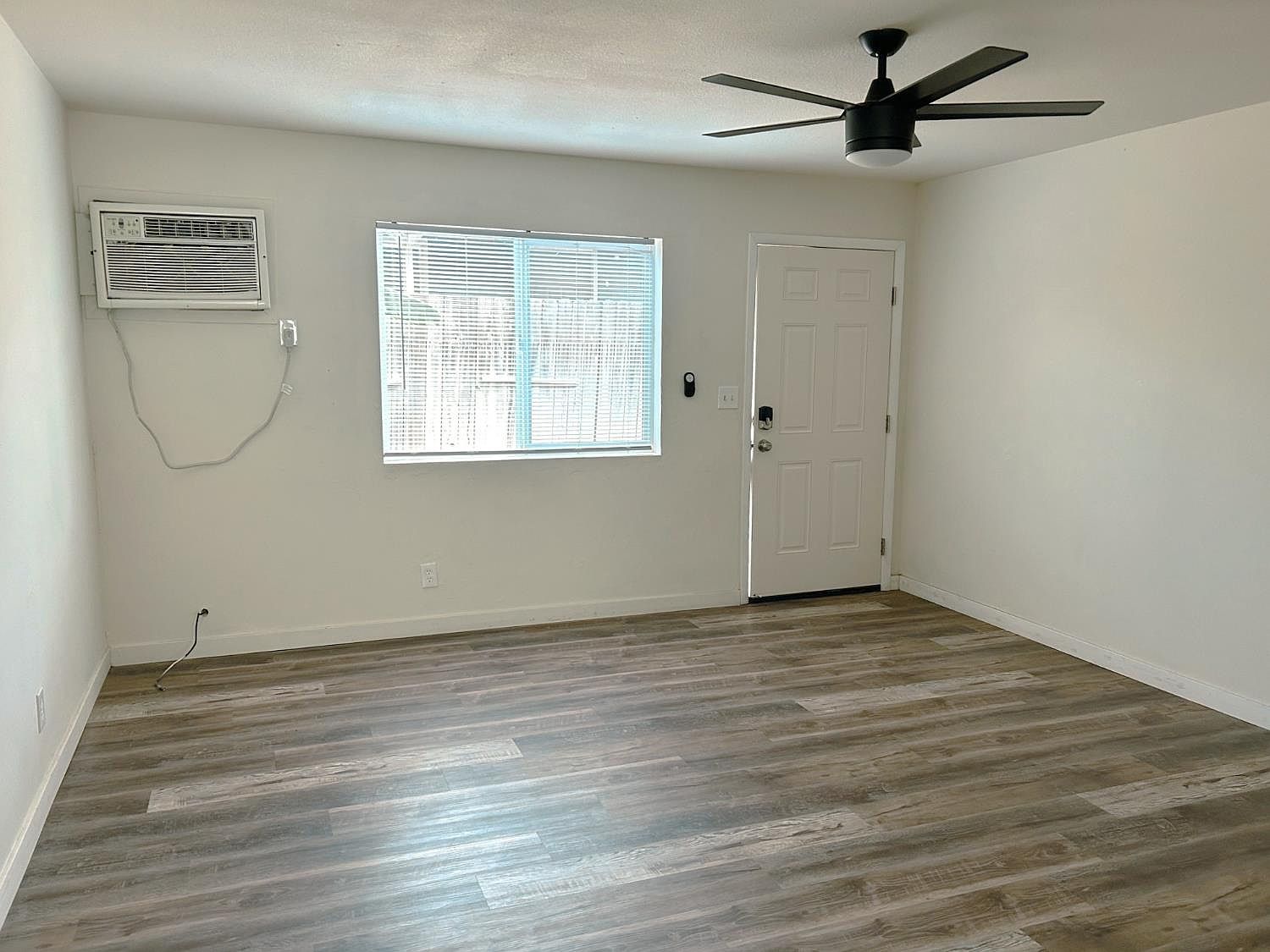 Living room with wall air conditioner and front entry door