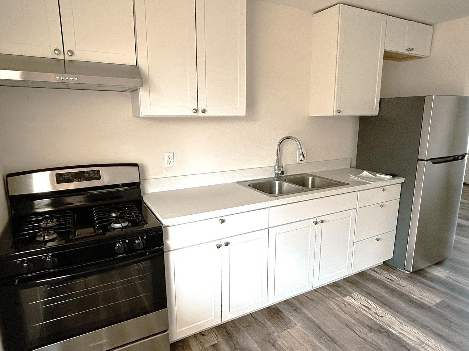 Renovated kitchen with stainless gas range and white shaker cabinets