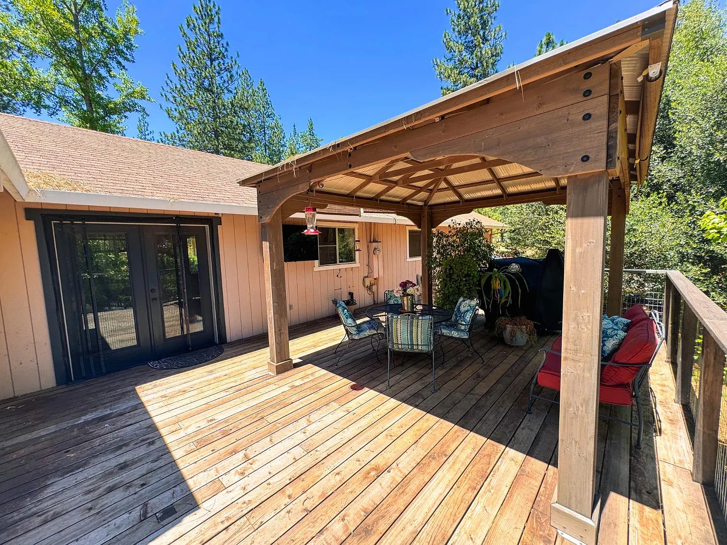 Covered deck with pergola shading outdoor seating alongside the house