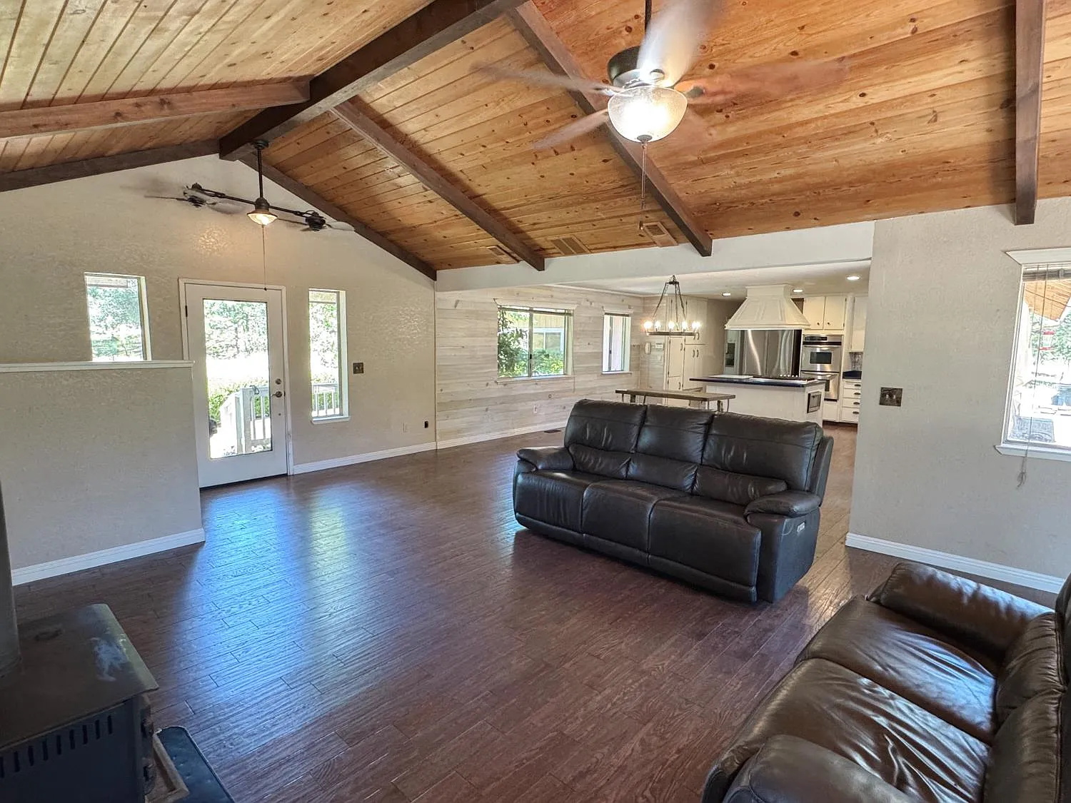 Great room with open beam vaulted ceiling in tongue-and-groove wood, dark wood floors and french doors