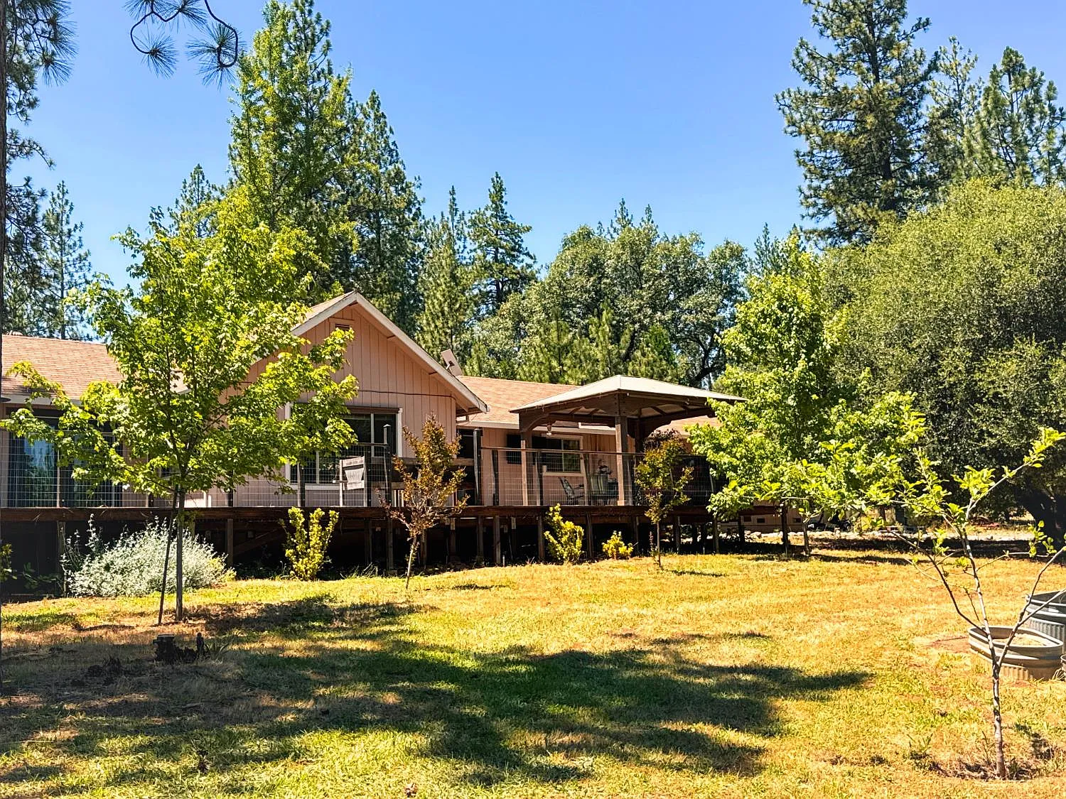 6425 Quartz Mine Rd seen from the cleared lawn, single-storey home among tall pines